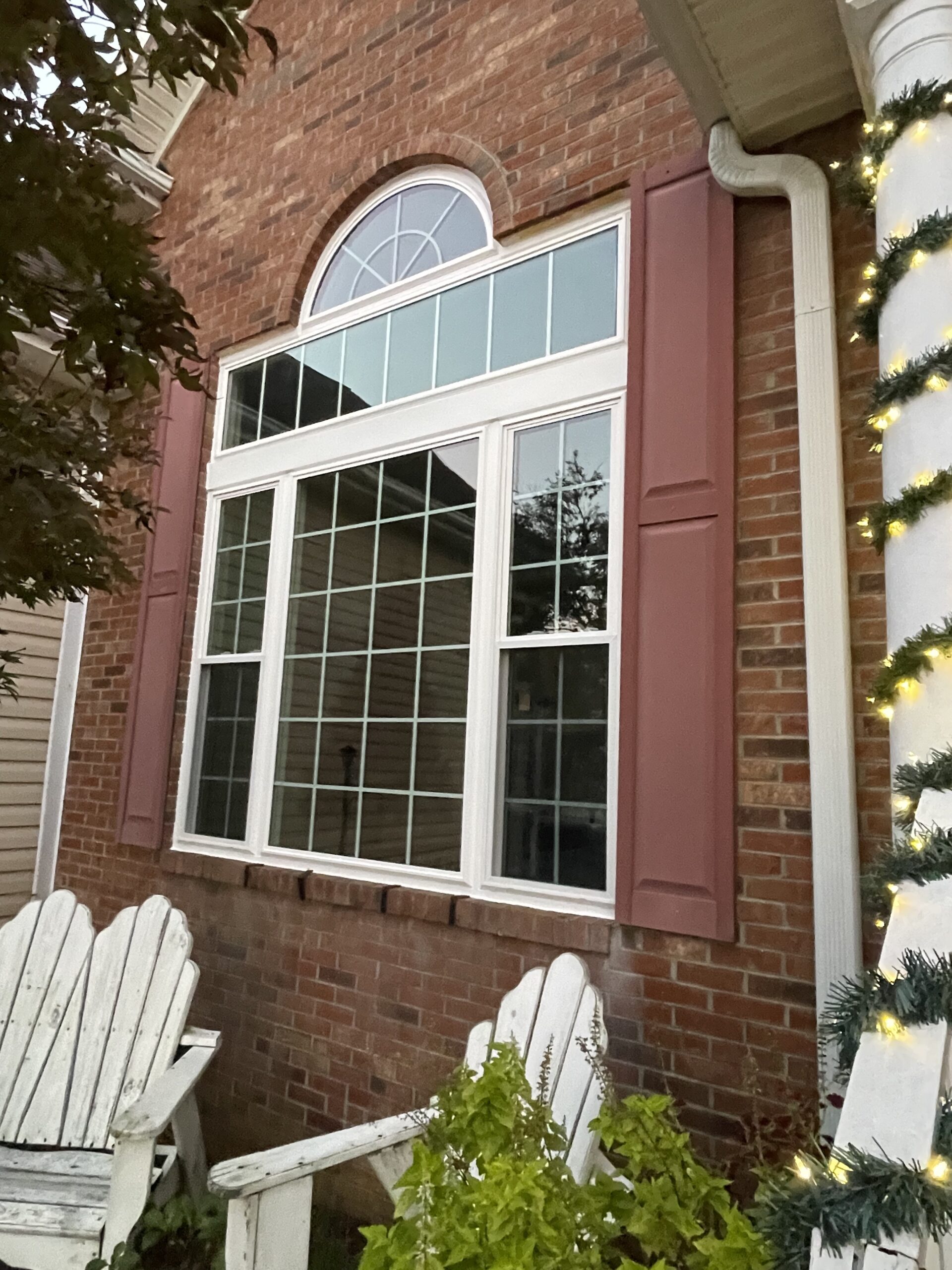 Arched replacement window installation on a home exterior